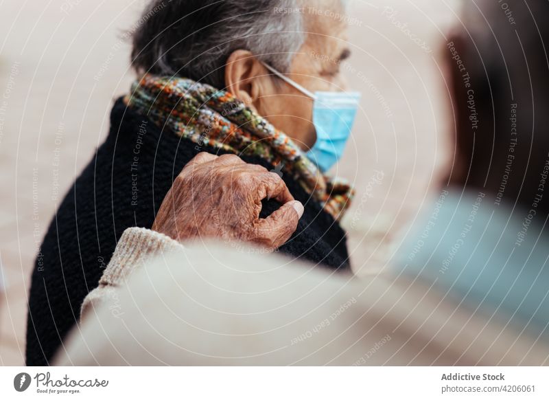 Elderly couple sitting on a park bench hand person man senior woman lifestyle outdoors husband together caucasian old elderly mature shoulder retired retirement