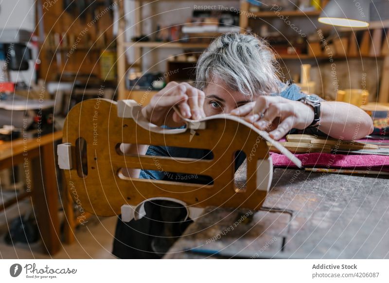 Craftswoman making violin in workshop craftswoman carve professional production curve instrument workbench female artisan apron body lamp studio job skill