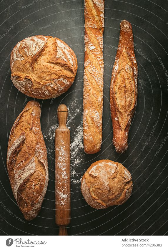 Fresh bread loaves and rolling pin on table loaf baked set various rustic food fresh bakery baguette round flour different natural cuisine nutrition crust