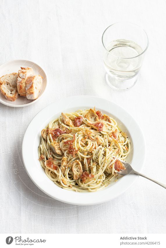 Closeup of a plate of spaghetti with artichokes seen from above food fresh cheese pepper ham vegetable pasta prosciutto vegetarian dinner herb cream cuisine