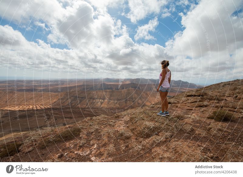 Unrecognizable woman standing on hilltop and admiring hilly landscape traveler hike highland valley nature rocky hiker casual mountain scenic spacious clear