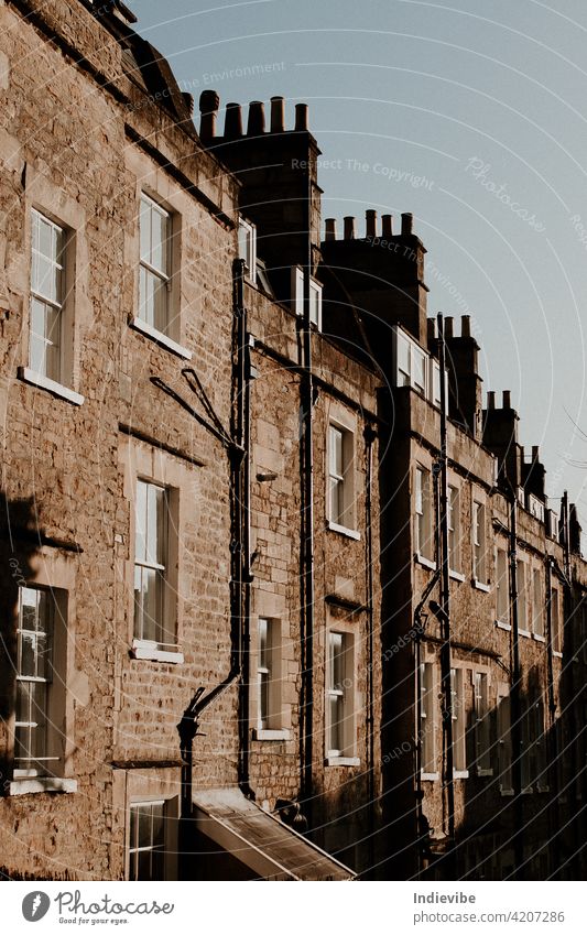 Street view of houses built together. Brick wall, outside drains, white windows and chimneys on a sunny day. building architecture old city urban town street