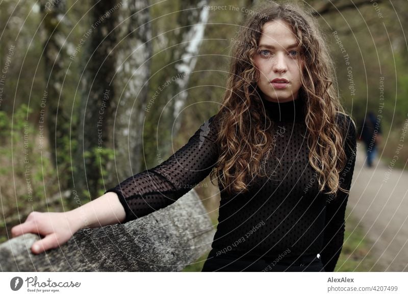 Portrait of a young woman with long, brunette, curly hair in front of a moor landscape on a bench Woman Young woman 18 - 30 years pretty Beauty & Beauty