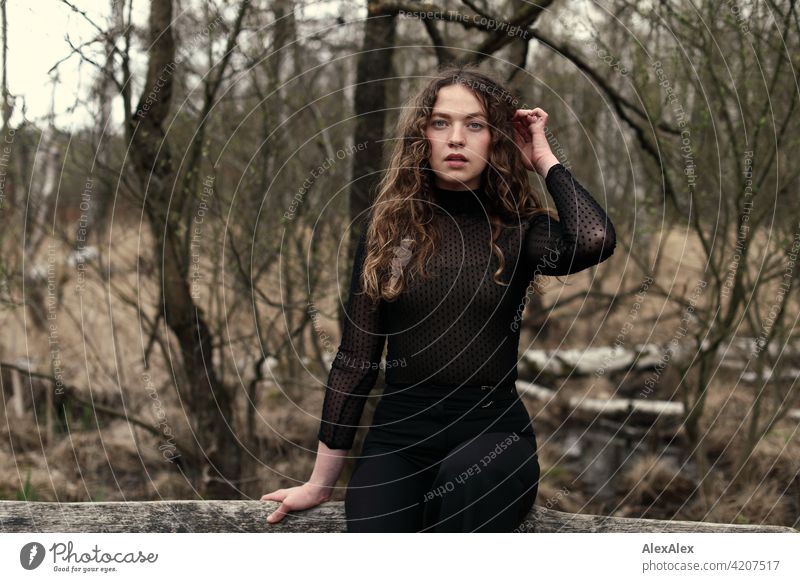 Portrait of a young woman with long, brunette, curly hair in front of a moor landscape on a bench Woman Young woman 18 - 30 years pretty Beauty & Beauty