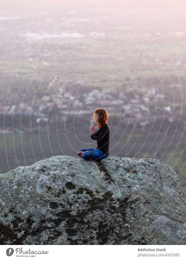 Young female in Lotus pose meditating on hilltop woman yoga sunset cliff lotus pose meditation padmasana vitality zen practice harmony flexible energy twilight