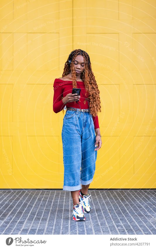 Black woman standing listening to music near huge doors in city doorway entrance building ancient old street female ethnic black african american using wooden