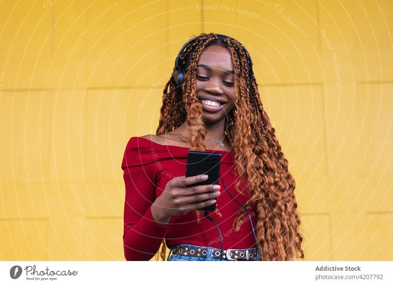 Black woman listening to music near yellow doors in city doorway entrance building ancient street female ethnic black african american using wooden huge