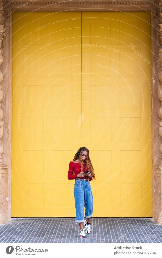 Black woman standing listening to music near huge doors in city doorway entrance building ancient old street female ethnic black african american using wooden