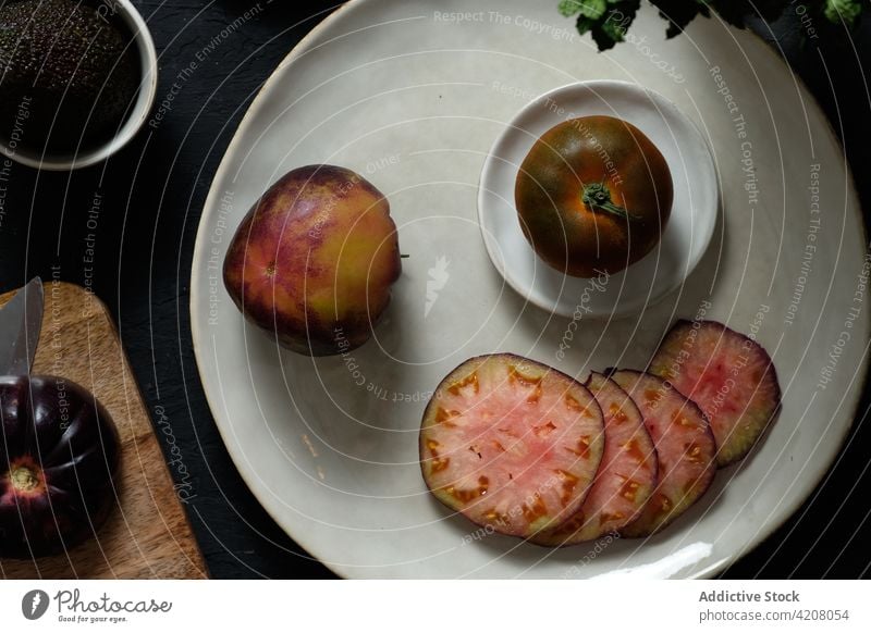 Black tomatoes and avocado on table mint fresh vegetable food prepare black natural healthy meal ingredient organic vitamin culinary nutrition product raw knife