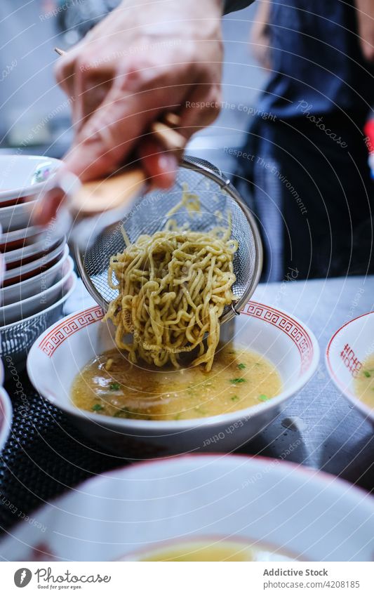 Ramen Soup Preparation in Restaurant ramen restaurant kitchen soup noodles yummy delicious japanese food plate strainer unrecognized front view faceless pouring