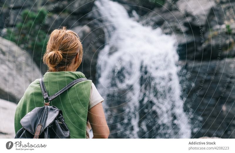 Unrecognizable woman standing near cascade in highlands trekking tourism waterfall nature female activity pyrenees adventure splash backpack admire trip flow