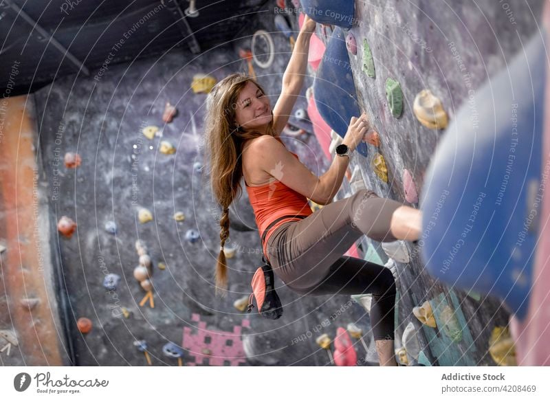 Active woman clambering wall in gym sportswoman bouldering focus extreme concentrate strength training strong mountaineer active sporty climber determine