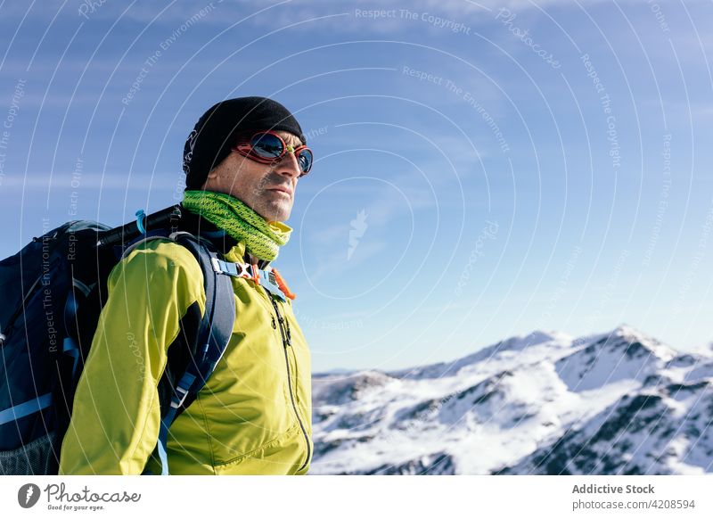 Traveler with backpack admiring snowy mountains traveler mountaineer man rock active climber sunlight nature freedom male activewear landscape sunny winter