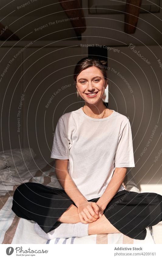 Smiling young woman relaxing on cozy bed in sunny morning smile enjoy bedroom positive happy comfort home glad female casual optimist rest sunlight delight