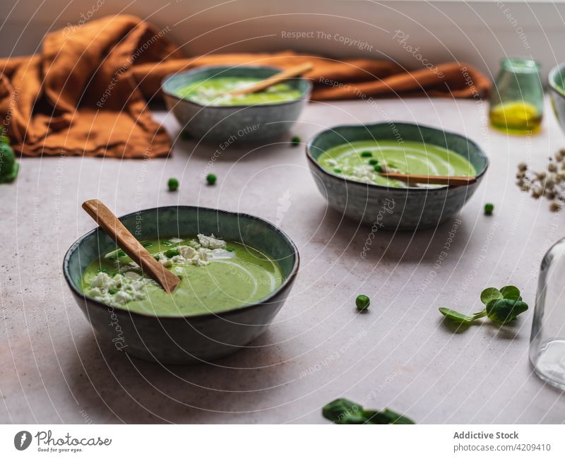 Tasty pea soup in bowls on table cream green delicious serve dish fresh organic tasty food meal gourmet healthy healthy food vegetarian vegan napkin vase flower