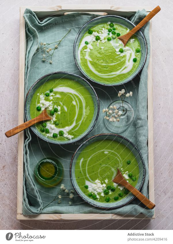 Tasty pea soup in bowls on table cream green delicious serve dish fresh organic tasty food meal gourmet healthy healthy food vegetarian vegan napkin vase flower