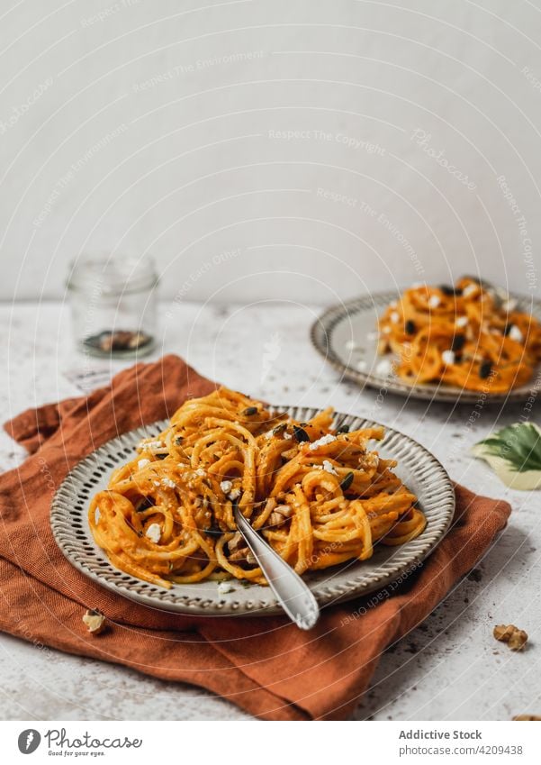 Appetizing pumpkin pasta in plate on table noodle dish lunch orange food serve tasty meal yummy ingredient cuisine nutrition seed garnish fresh palatable