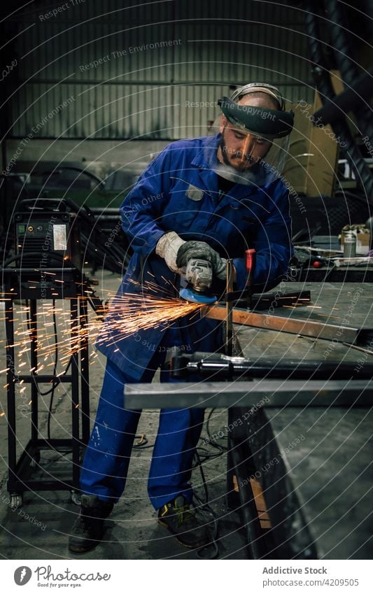 Man processing metal detail in workshop man welder angle grinder spark worker construction professional workwear mask equipment male light workspace workman