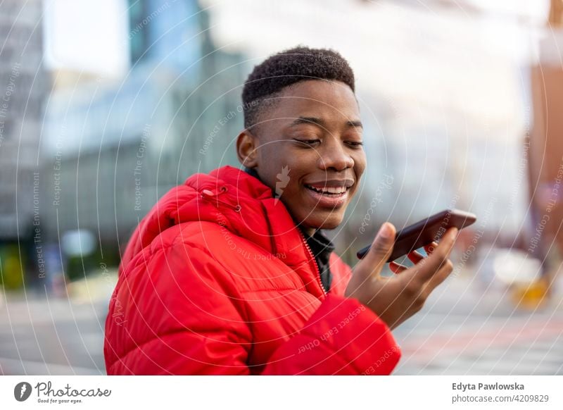 Young man using smart phone outdoors at urban setting black outside street millennial standing African city Warsaw real people casual lifestyle guy attractive