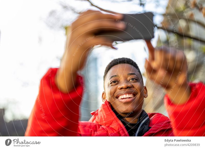 Young man using smart phone outdoors at urban setting black outside street millennial standing African city Warsaw real people casual lifestyle guy attractive