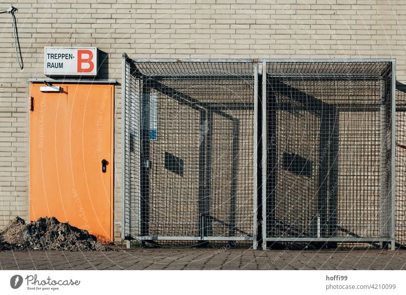 orange door to the staircase with lattice boxes on a construction site Orange Staircase (Hallway) grid box Grating shadow cast Construction site Fence Barrier