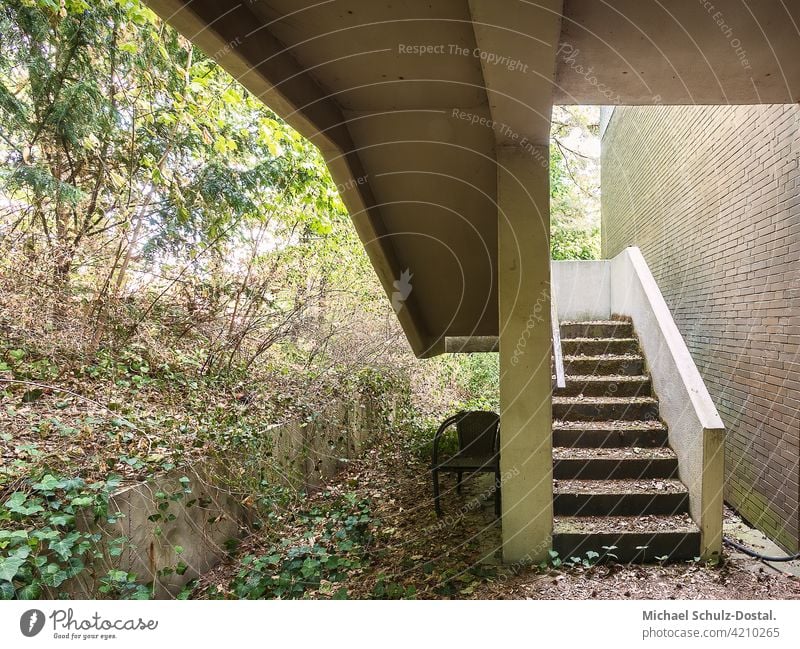 Architectural outdoor staircase with clear lines and garden vegetation abandoned Urbex lostplace rot decay forsake sb./sth. decoration interior Ruin surface