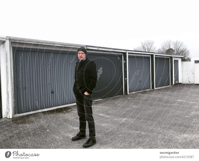 Monochrome garage-guy Man garages Garage Garage door Parking lot posing Gray Black Large Vanishing point Goal Gloomy boringly Closed Highway ramp (entrance)