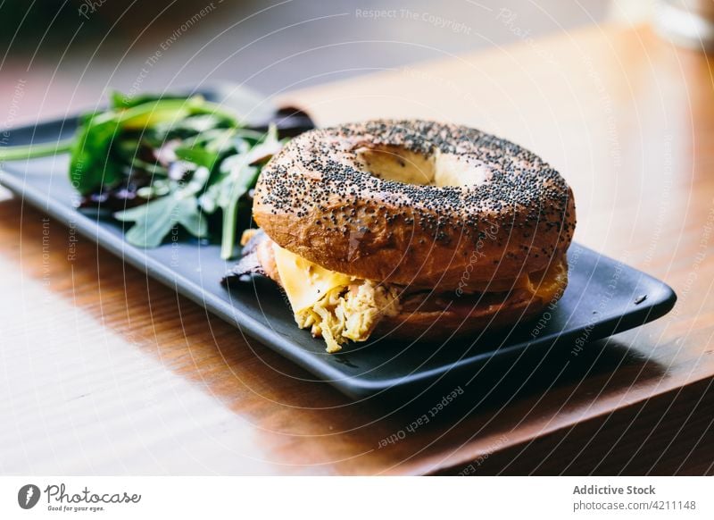 Tasty bagel sandwich on table in cafe meat serve tasty chicken appetizing food meal delicious salad plate rucola arugula cheese culinary nutrition portion