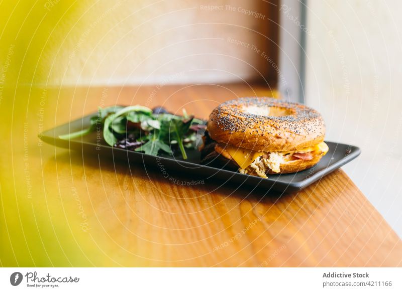 Tasty bagel sandwich on table in cafe meat serve tasty chicken appetizing food meal delicious salad plate rucola arugula cheese culinary nutrition portion