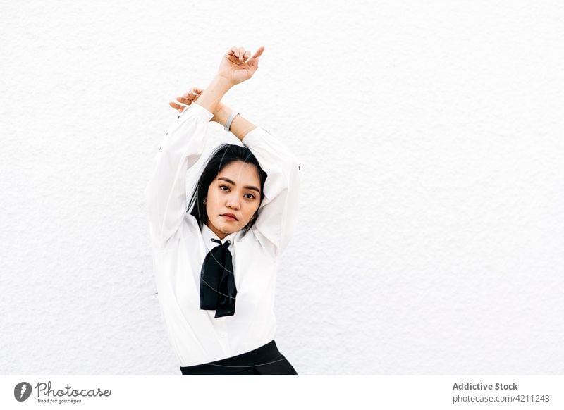 Confident Asian woman with hands crossed above head student uniform cool confident stare individuality posture elegant gaze female arms crossed teen thoughtful