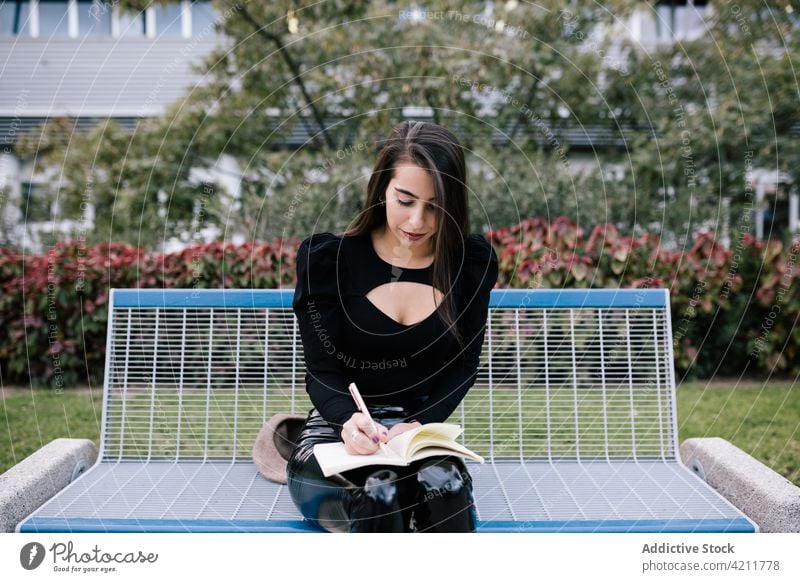 Businesswoman sitting on bench with notebook businesswoman take note park urban city work write entrepreneur female organizer diary notepad smart freelance