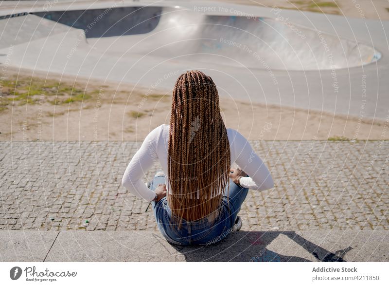 Stylish ethnic woman in rollerblades in skate park cool summer hobby trendy ramp braid black african american style denim carefree urban jeans lady enjoy sunny