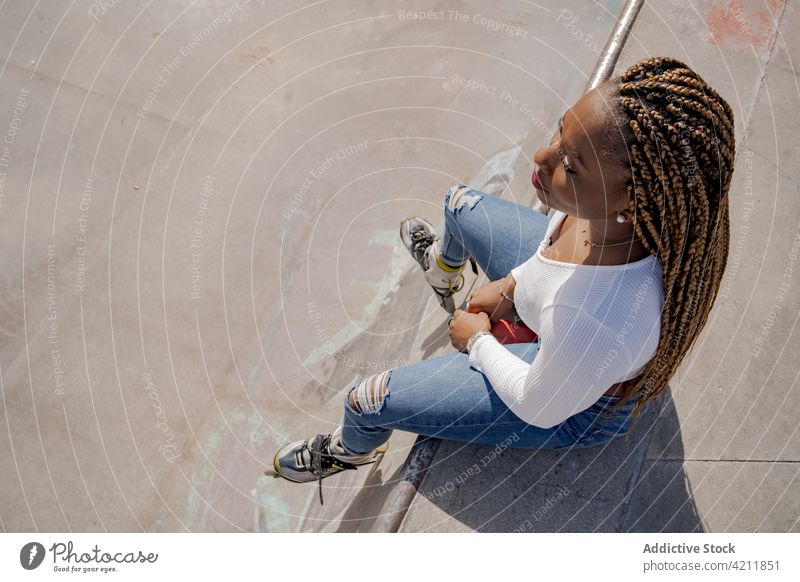 Stylish ethnic woman in rollerblades in skate park cool summer hobby trendy ramp braid black african american style denim carefree urban jeans lady enjoy sunny