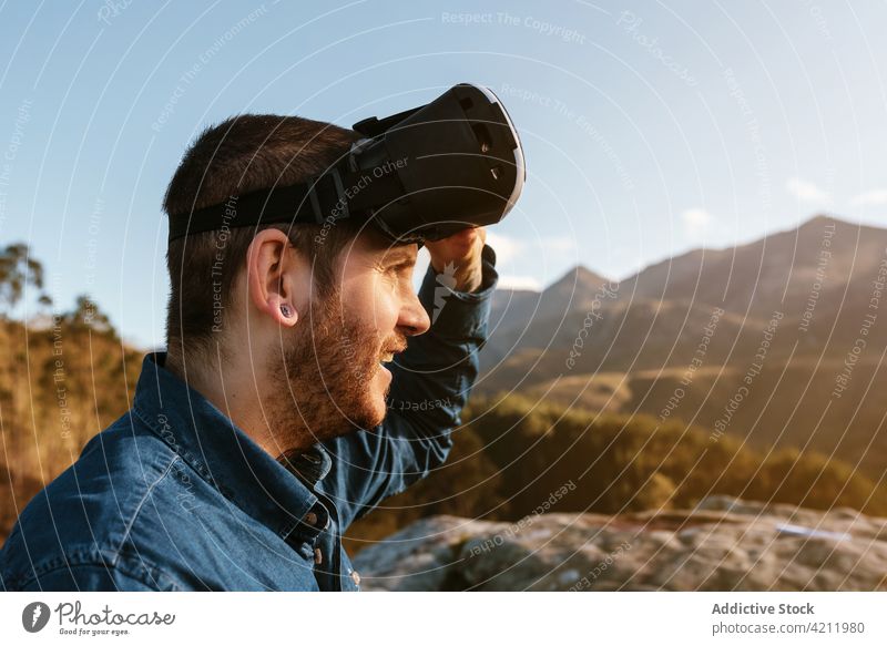 Traveling man using VR glasses in mountains traveler virtual reality experience vr highland goggles male adventure enjoy hill explore trip nature sit device