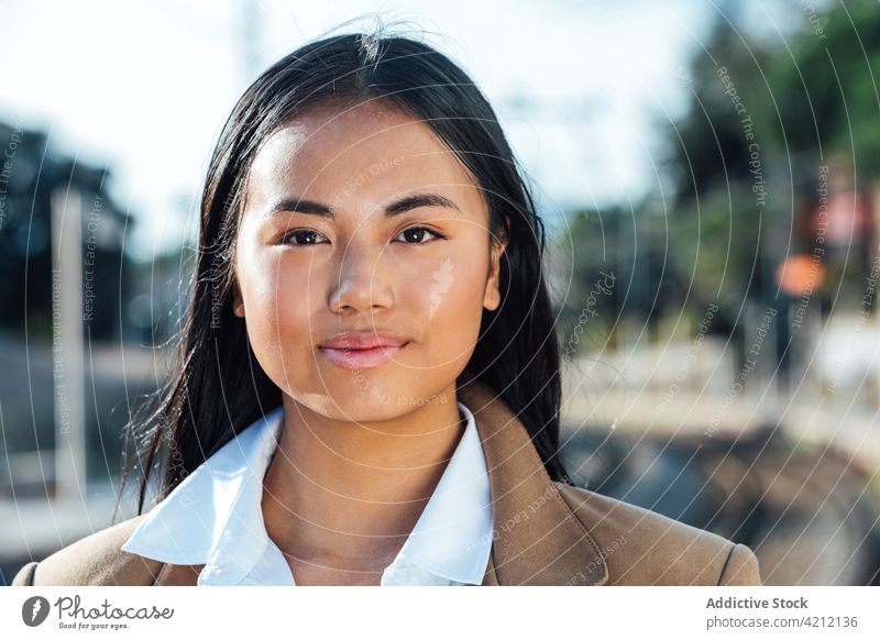 Positive ethnic woman standing at railway station and looking at camera traveler smile railroad platform train content female asian journey vacation public