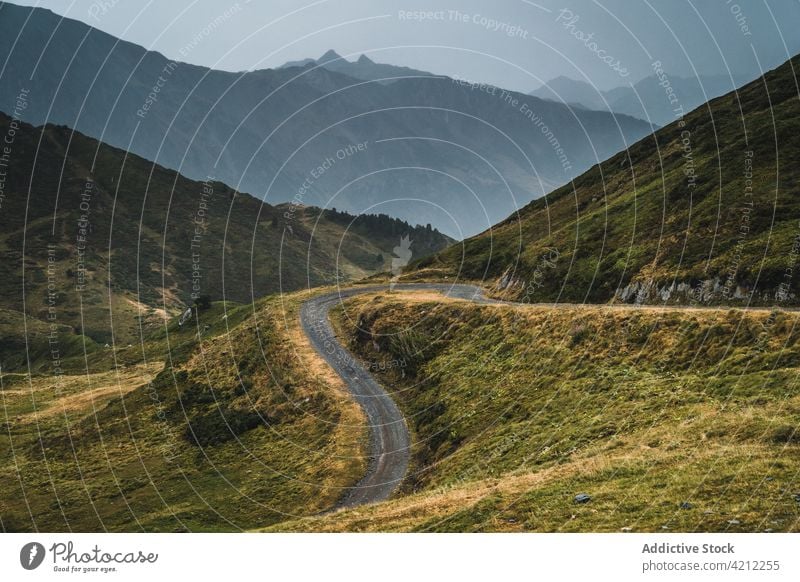 Road in majestic valley of Pyrenees mountains landscape road grass pyrenees highland cloudy sky nature hill val d arana picturesque empty dry green plant path