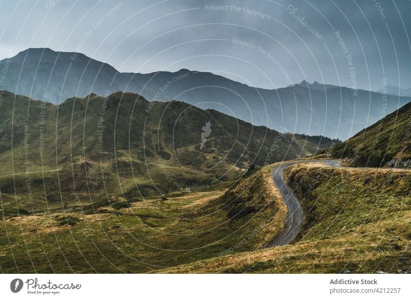 Road in majestic valley of Pyrenees mountains landscape road grass pyrenees highland cloudy sky nature hill val d arana picturesque empty dry green plant path