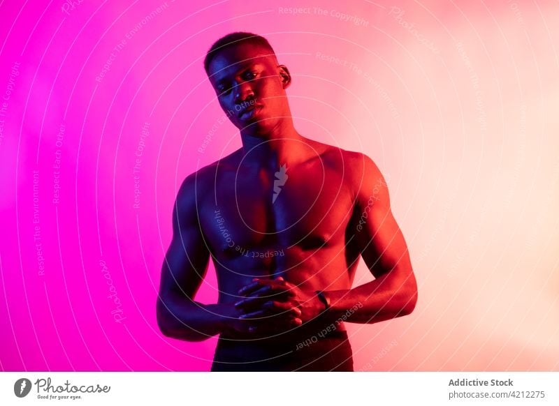 Emotionless shirtless black guy on pink background man sporty muscular serious athlete emotionless neon studio shot confident african american male young muscle