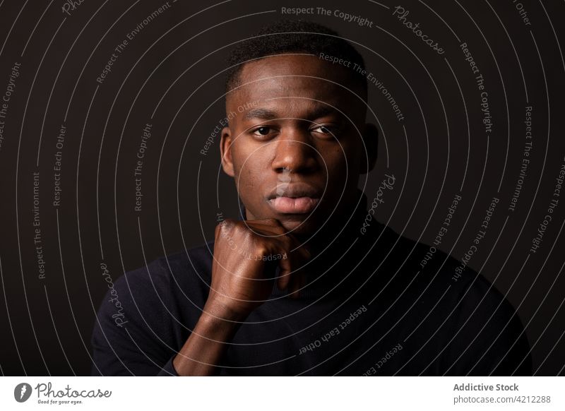 Thoughtful black man on black background portrait thoughtful studio shot emotionless alone serious hand at chin touch chin pensive african american male young