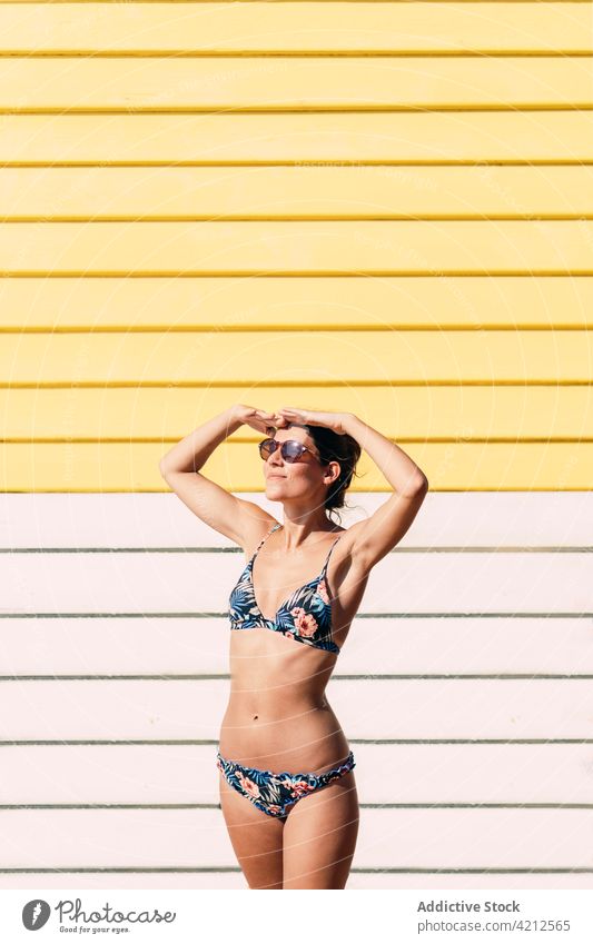 Smiling woman in bikini standing near bathing box summer sunny vacation sunbath suntan cheerful female melbourne australia sunglasses happy enjoy swimwear beach