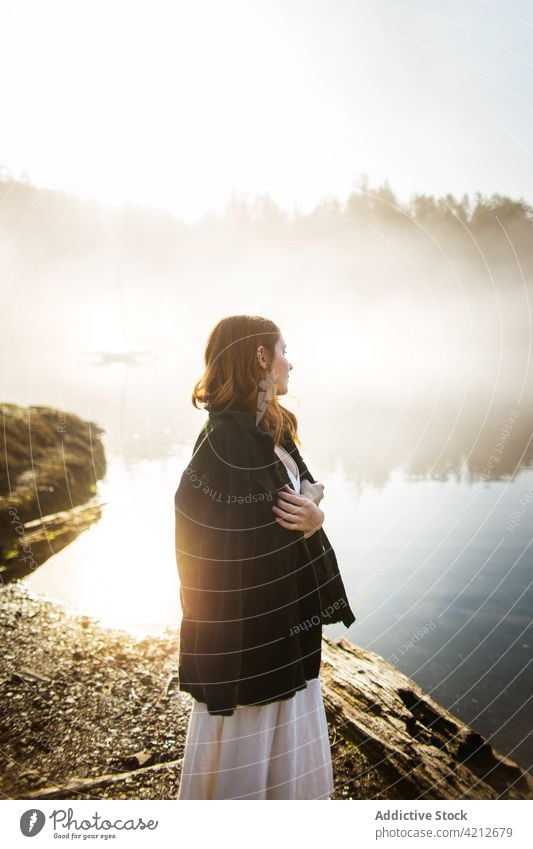 Woman standing on a rock looking at a lake on a foggy day nature woman mist water landscape people girl outdoor person female beautiful forest travel morning