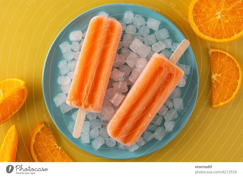 Orange popsicles on blue plate background cake cold colorful cool cream dessert flavor food fresh frosty frozen fruit homemade ice icecream iced juice lolly