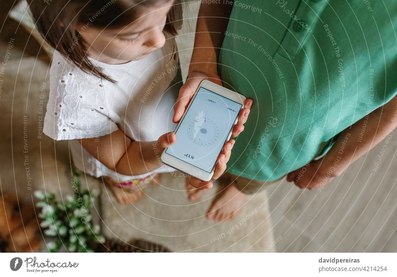 Boy and girl playing with the compass on the mobile top view boy looking cell phone smartphone app home family aerial children people brother kid sister two