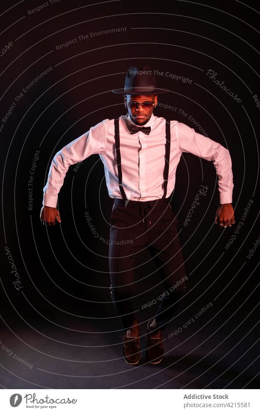 Stylish black man in white shirt and sunglasses dancing on black background model style fashion well dressed gentleman dance tiptoe masculine portrait macho