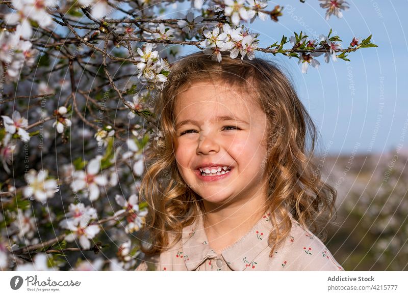 Cute little girl in blooming garden in spring flower tree portrait cheerful blossom floral dress park child cute smile kid happy childhood adorable glad joy