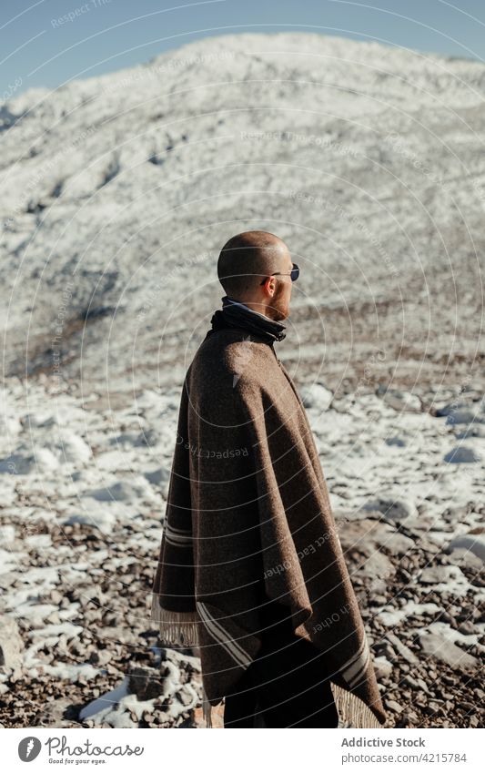 Traveler contemplating snowy ridge in sunlight traveler admire nature wanderlust highland landscape tourism winter man journey idyllic alone sunglasses mountain