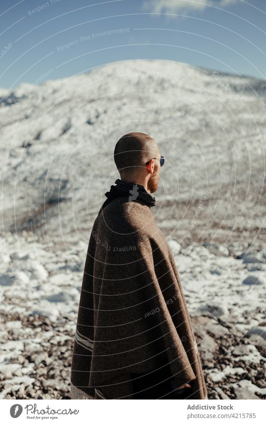 Traveler contemplating snowy ridge in sunlight traveler admire nature wanderlust highland landscape tourism winter man journey idyllic alone sunglasses mountain