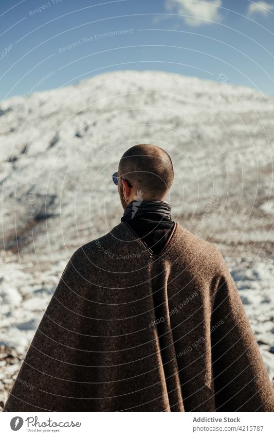 Unrecognizable traveler contemplating snowy ridge in sunlight admire nature wanderlust highland landscape tourism winter man journey idyllic alone sunglasses