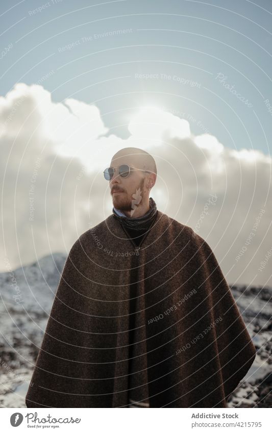 Traveler contemplating snowy ridge in sunlight traveler admire nature wanderlust highland landscape tourism winter man journey alone sunglasses mountain slope