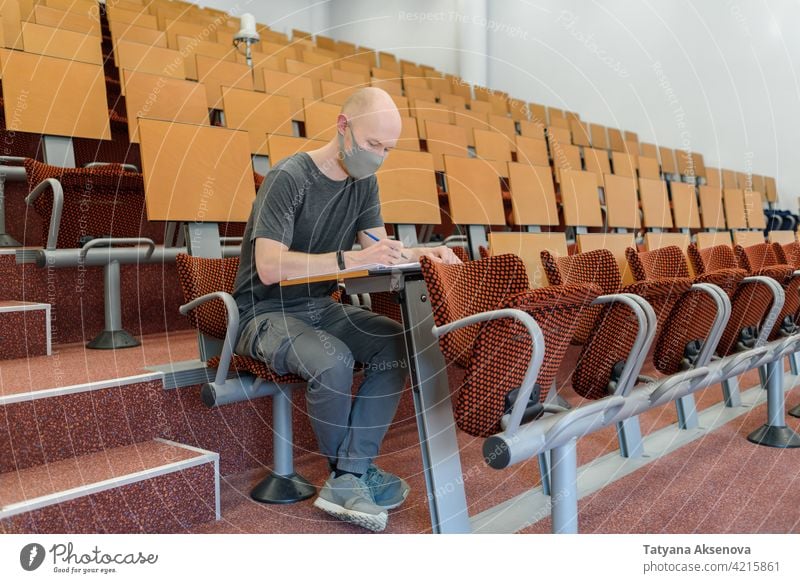 Man student sitting in face mask education classroom studying back to school high school learning safety male person indoors protection social distancing